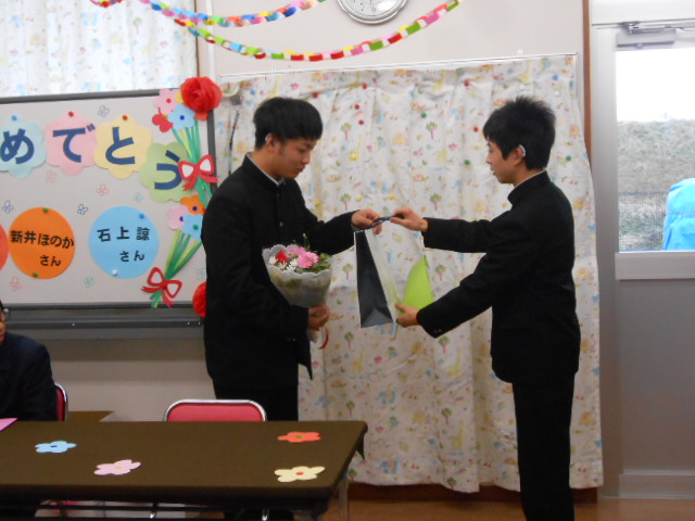 卒業生に記念品を渡す男子
