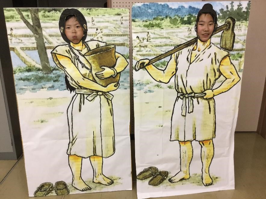 弥生人の顔出しパネルで顔を出している様子