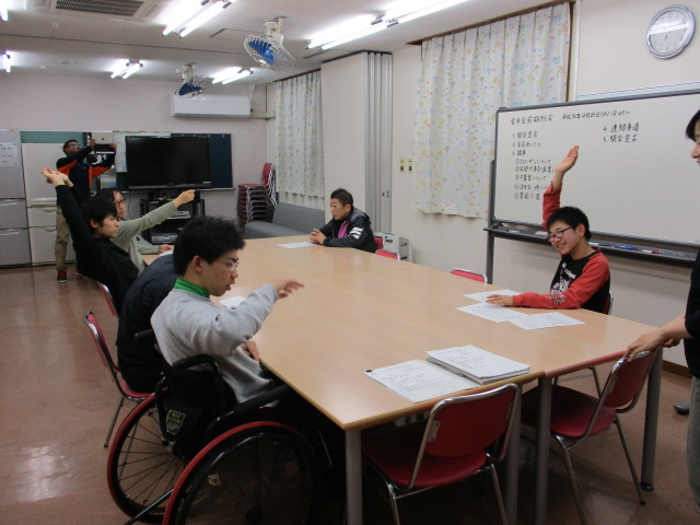 総会で賛成の挙手をしています。