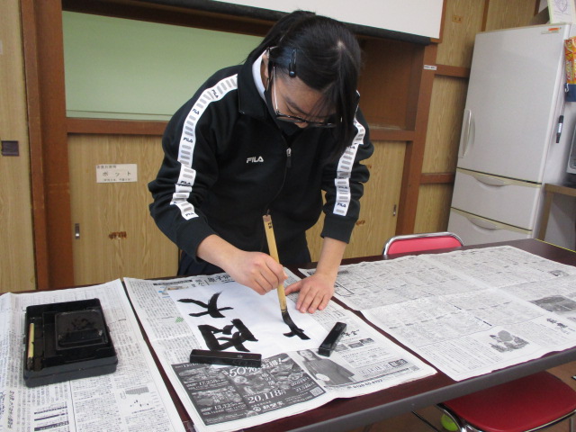 聾生が書初めを行う。