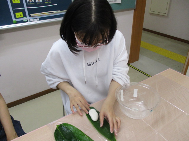 舎生が団子を笹に包んでいる