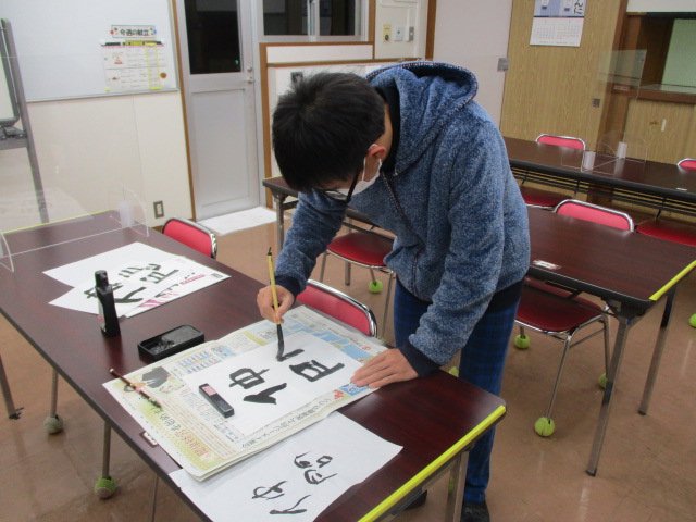 男子舎生が「仲間」と書いている様子