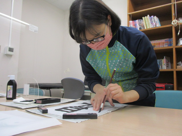 女子舎生が筆で文字を書いている様子