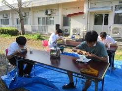 屋外でピザを食べている舎生