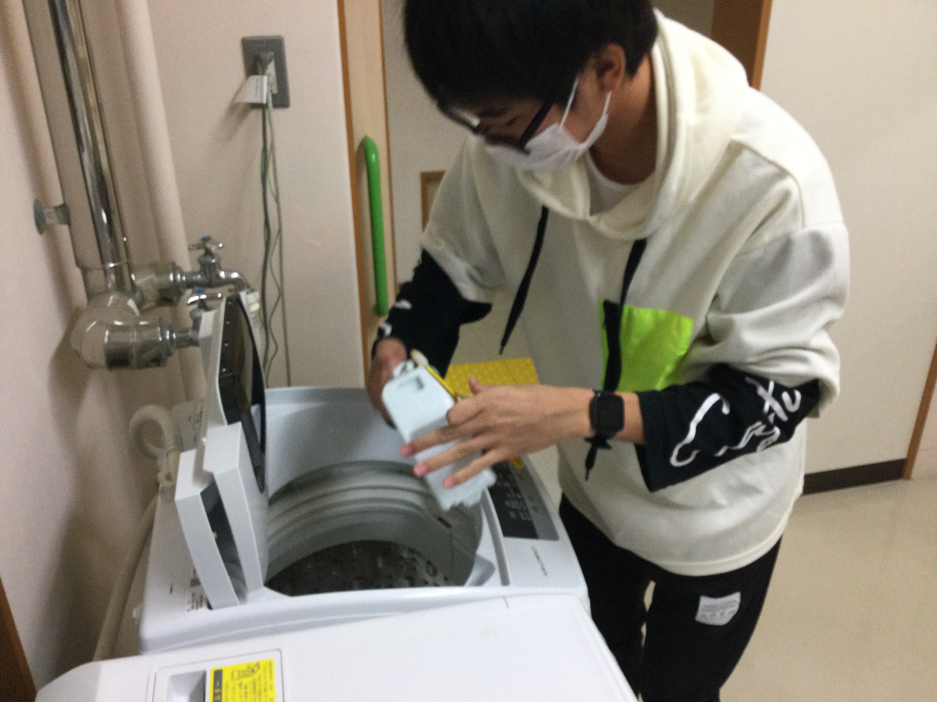 洗濯機の糸くずを掃除する舎生