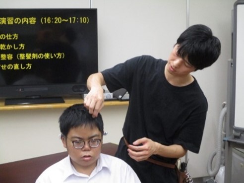 講師が整髪剤を使い、生徒の髪を整えている様子