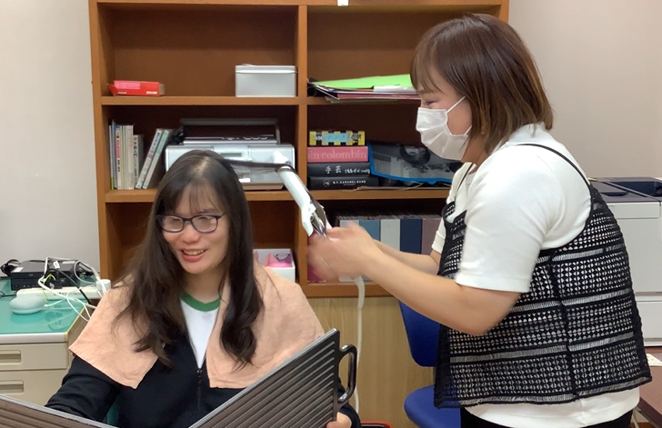 講師がヘアーアイロンを使い、舎生の髪を整えている様子